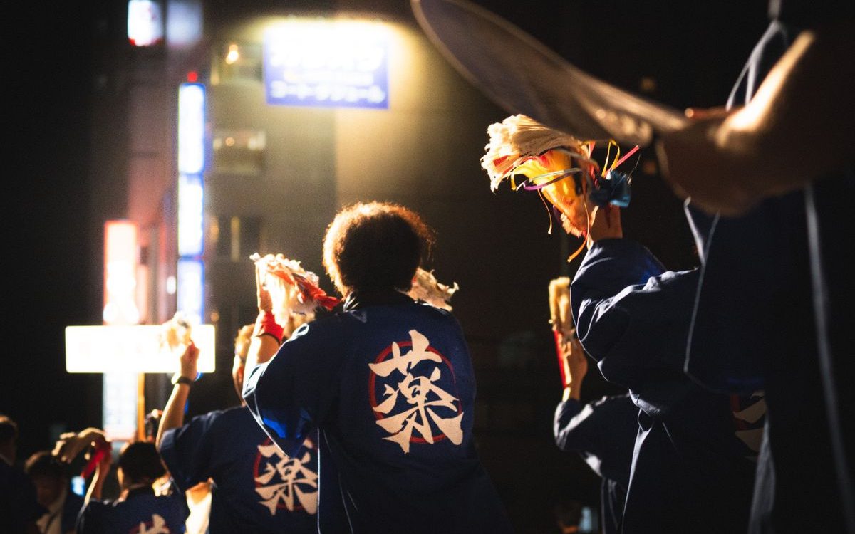 夜の祭りで鉦と太鼓を打ち鳴らす踊り手たち