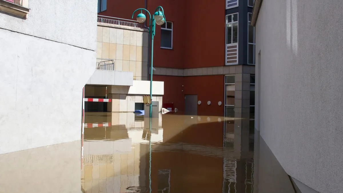 建物に囲まれた市街地の道路が茶色く濁った水に覆われ、水面に建物が映っている