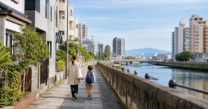 福岡市の川沿いの住宅地を親子で歩く様子