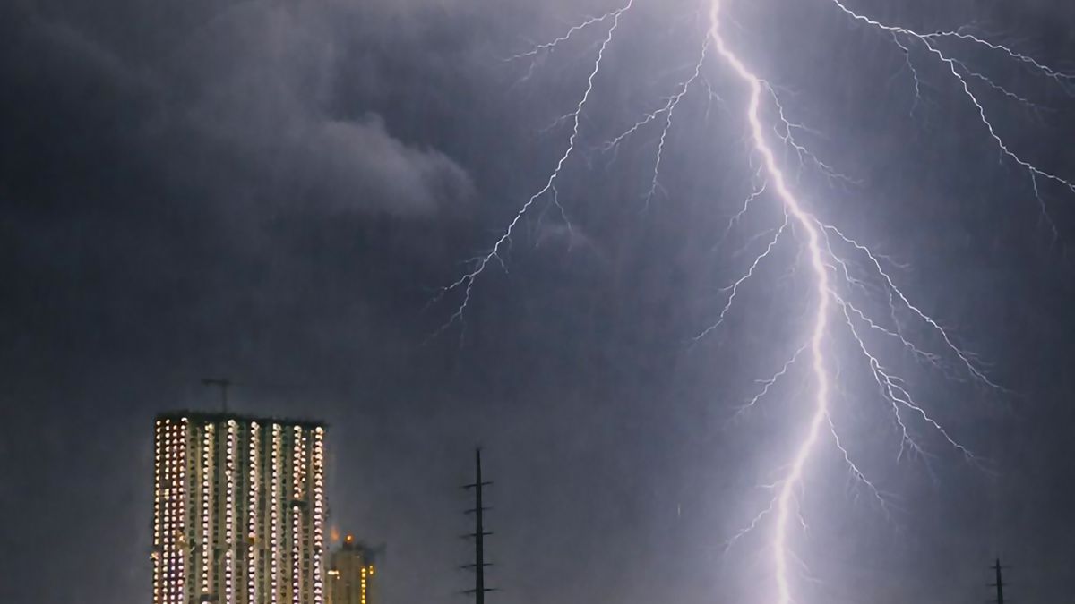 市街地のビル群に落ちる雷。空は厚い雨雲におおわれている