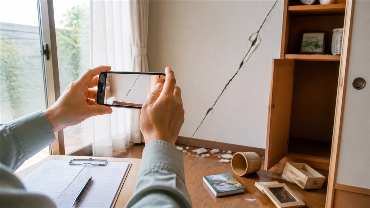 地震でできた室内の壁のひびをスマートフォンで撮影する様子
