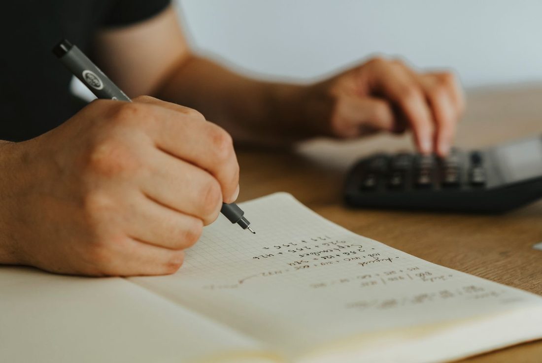 ノートに数字を書きながら電卓を打つ手元