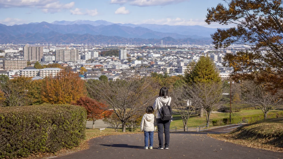 相模原台地の市街地と遠くの山並みを、公園から親子が見渡す暮らしのイメージ