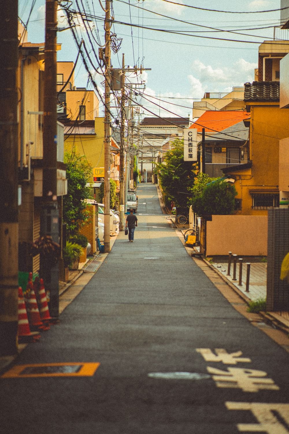 家が両側から迫る狭い道を人が歩いている