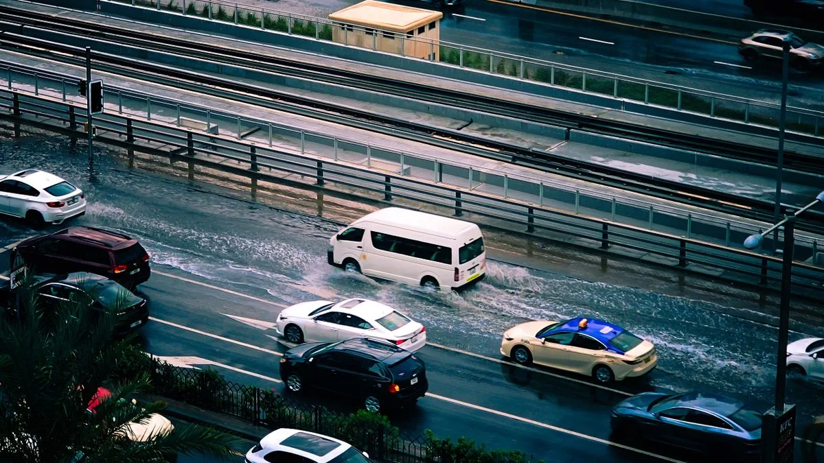 雨で水があふれた市街地の道路を、複数の車がゆっくり進んでいる