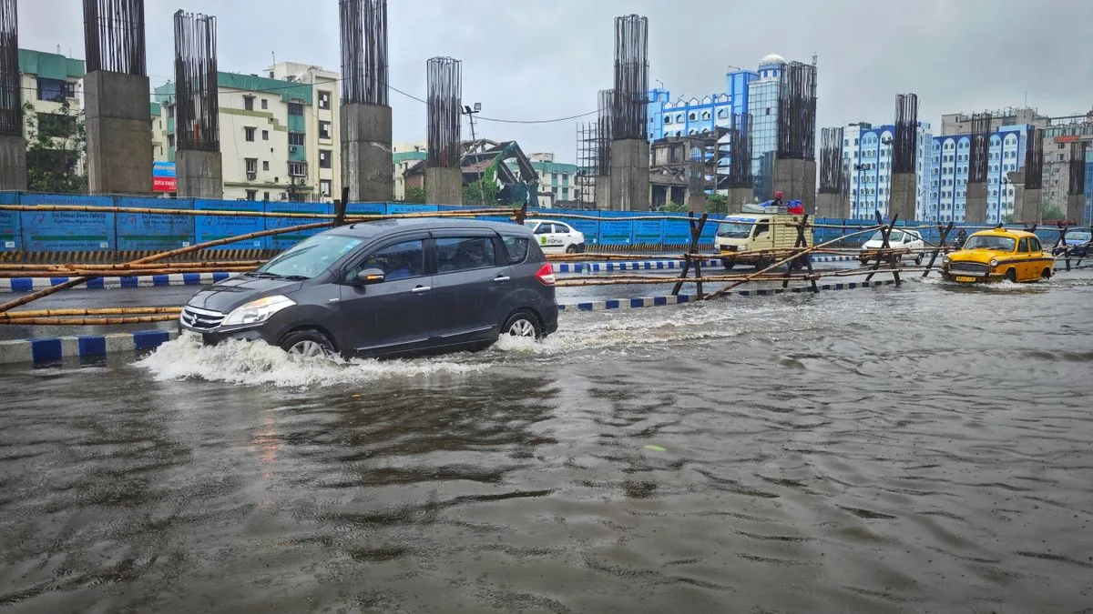 冠水した道路を進む車。周囲は工事現場の柵で囲まれ、水しぶきが上がっている