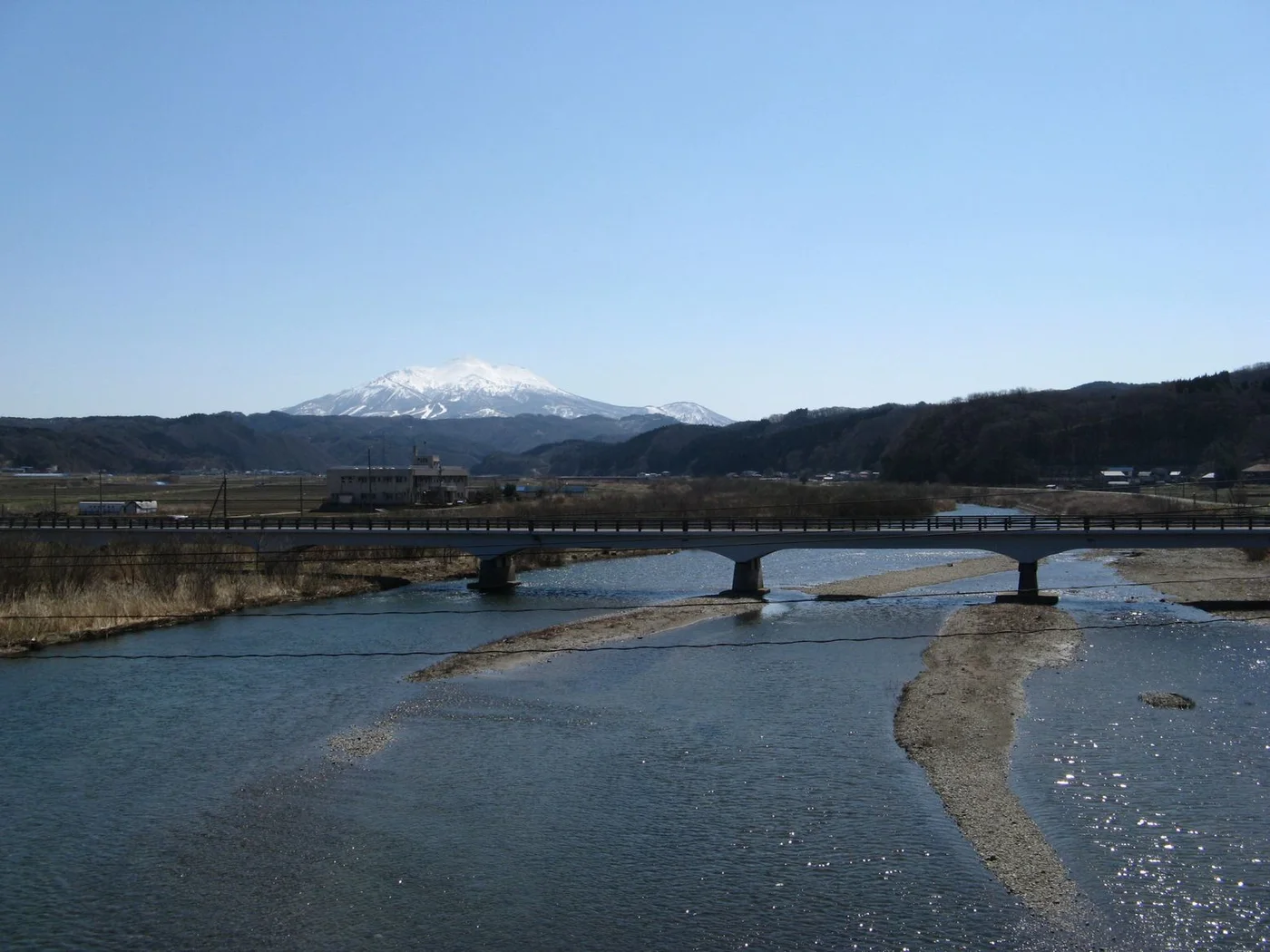 五能線の車窓から南東に見た赤石川。手前に川面と河原、背後に岩木山がそびえる