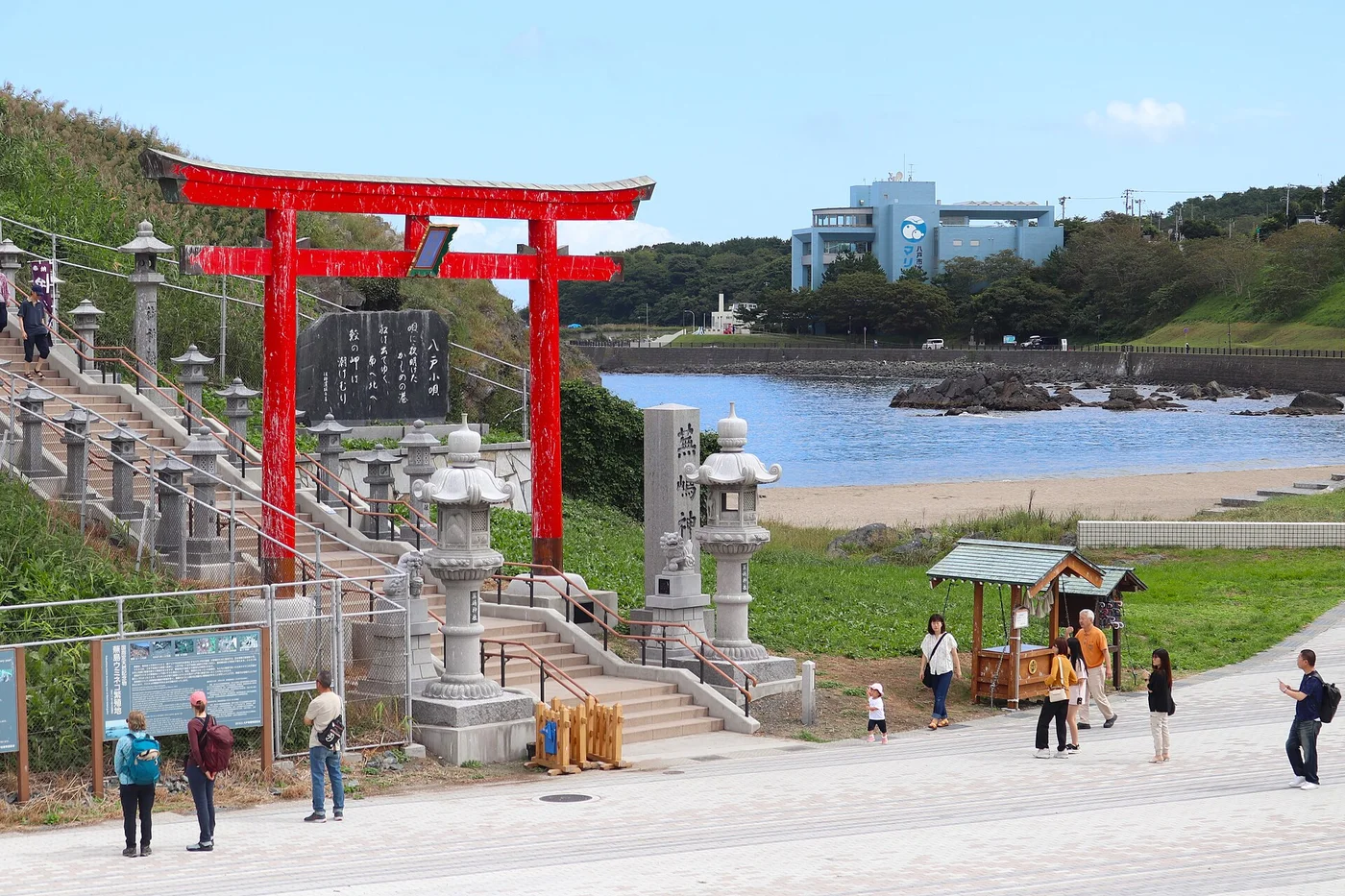 八戸市の蕪島神社と蕪島海水浴場。小高い島の上に社殿が建ち、手前に砂浜と海が広がる