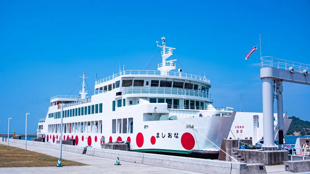 岸壁に接岸している白いカーフェリー。船体に赤い丸の模様が並んでいる