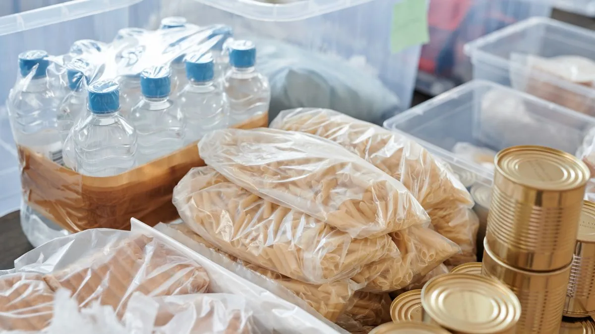 透明な収納箱に並べられたペットボトルの水と、袋に入った食品や缶詰