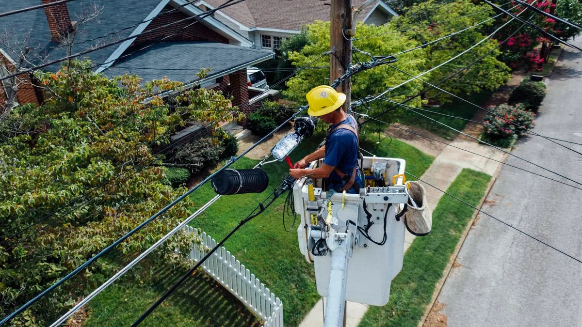 住宅街の電柱に高所作業車のバケットで登り、電線を直している作業員