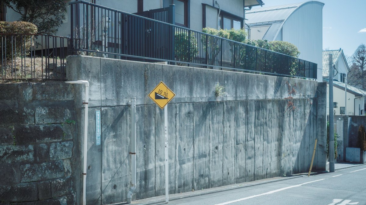 住宅地の急な坂と擁壁、勾配を示す標識