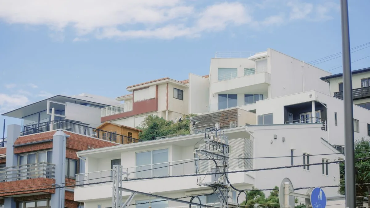 斜面に段々に建ち並ぶ日本の住宅。手前の家の下にコンクリートの擁壁が見える