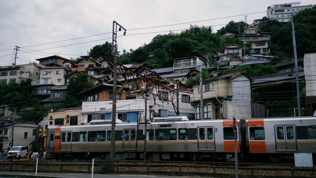 斜面いっぱいに住宅が建ち並ぶ日本の町。ふもとを電車が走っている