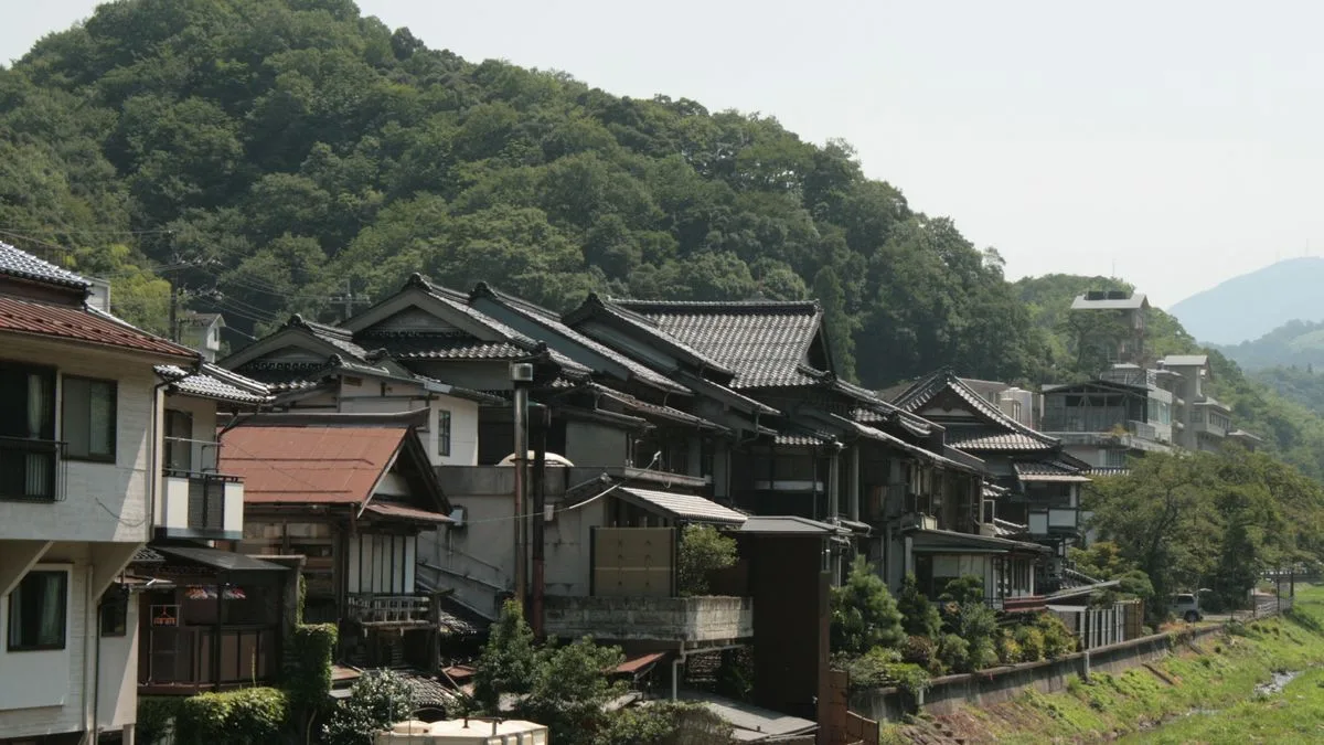 山の斜面のふもとに並ぶ瓦屋根の日本家屋