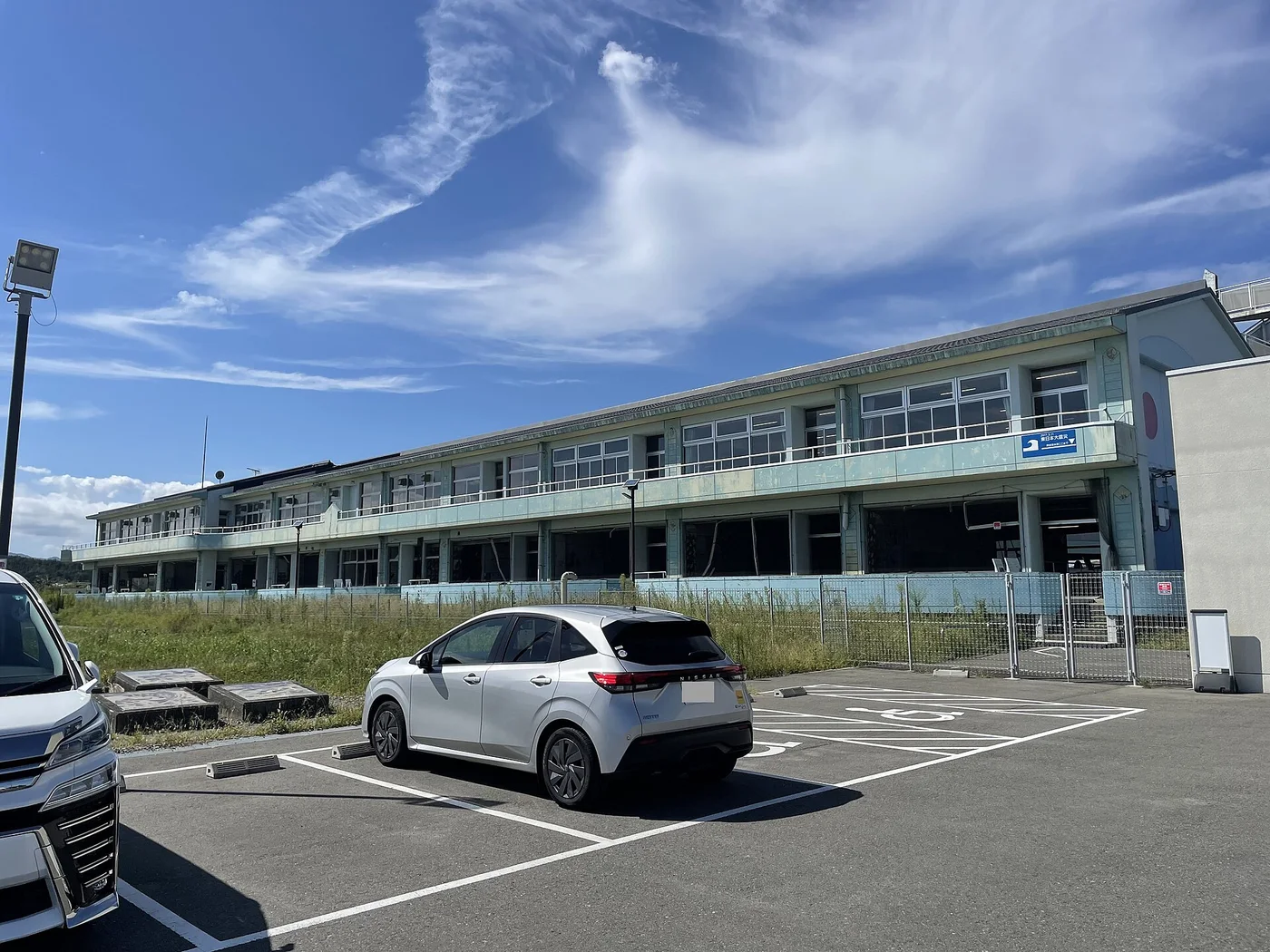 浪江町の請戸小学校の校舎。震災遺構として残された鉄筋コンクリートの建物と、その前に広がる草地