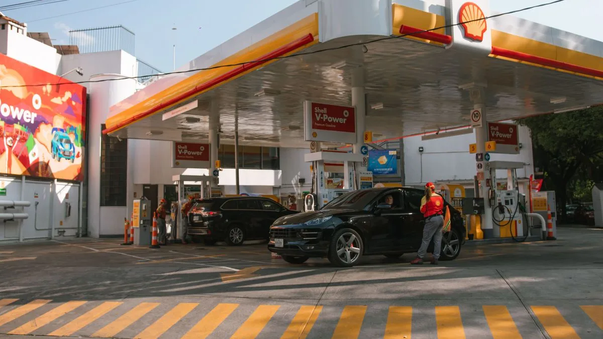 屋根のあるガソリンスタンドで、係員が車に給油している