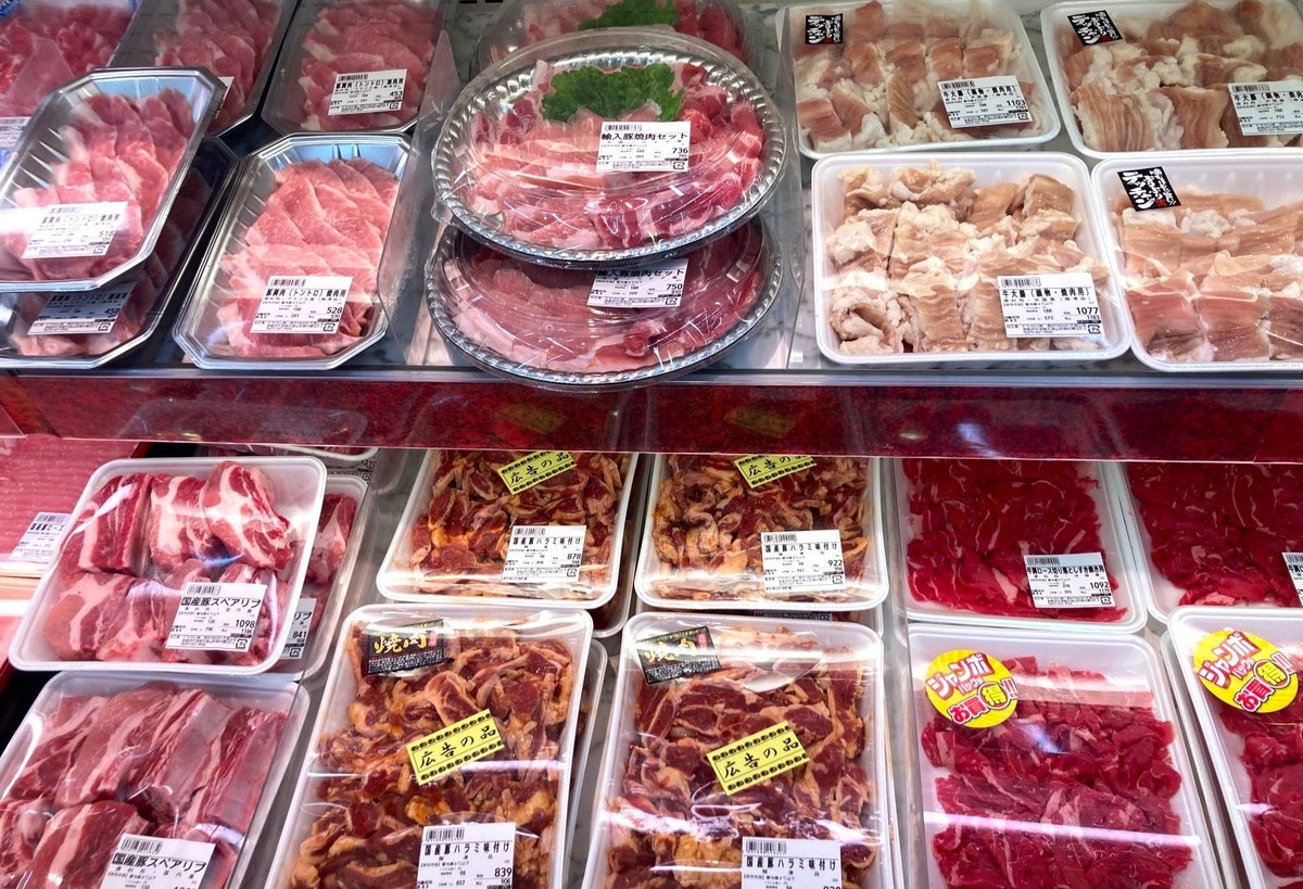 業務スーパーの精肉売場。パック詰めの肉が冷蔵ケースに並んでいる