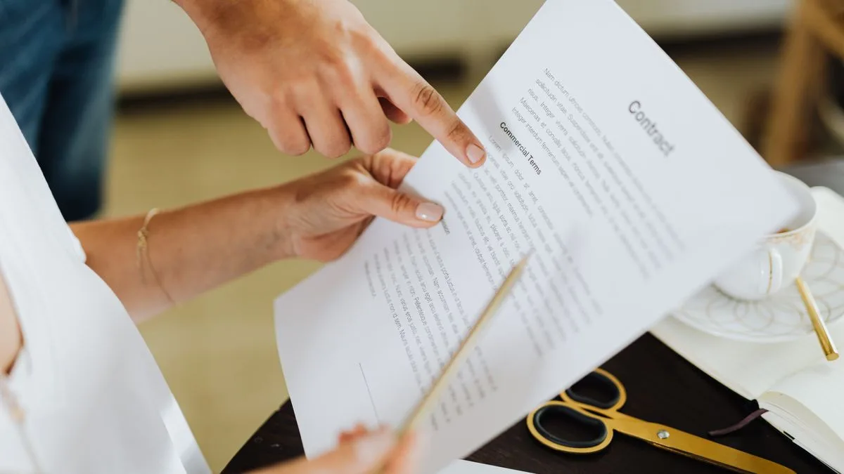 机の上の契約書を、二人が指をさしながら確認している手元