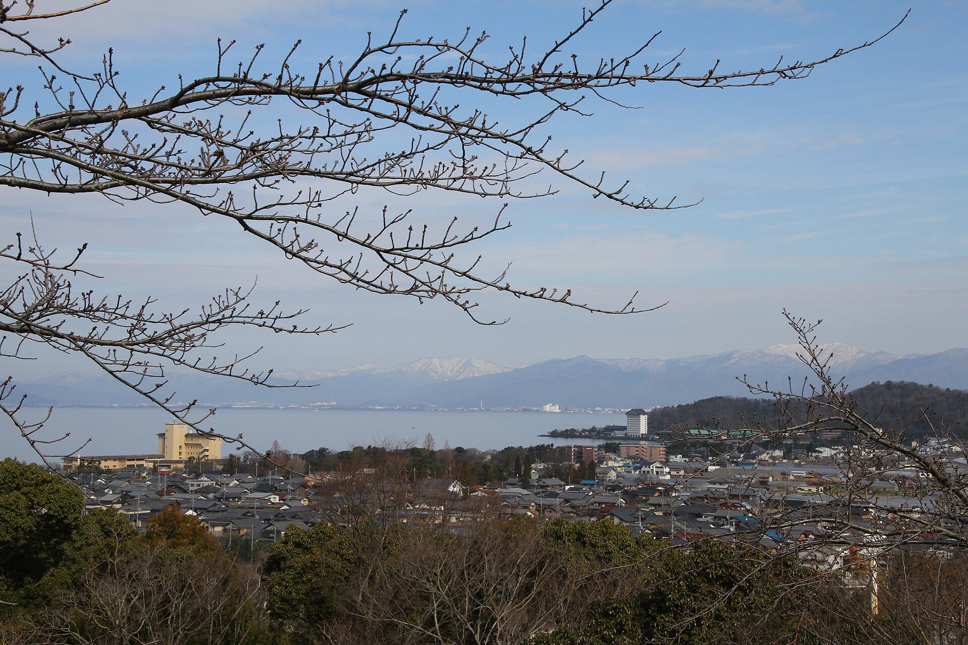彦根城から見下ろした彦根の市街地と琵琶湖。手前に瓦屋根の家並みが広がり、奥に湖と対岸の山並みが見える