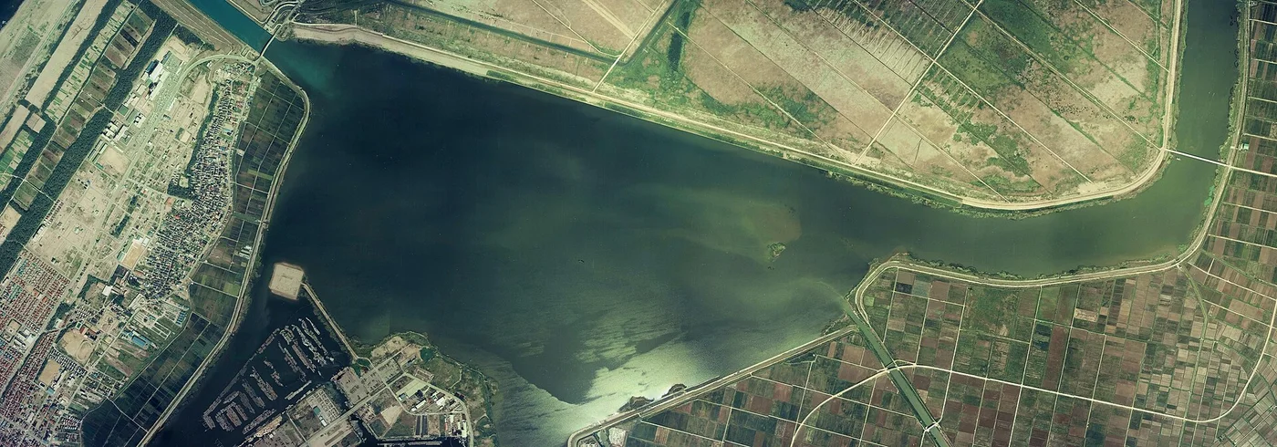 1975年に撮影された河北潟の空中写真。水面のまわりに直線の堤と、区画された農地が広がっている