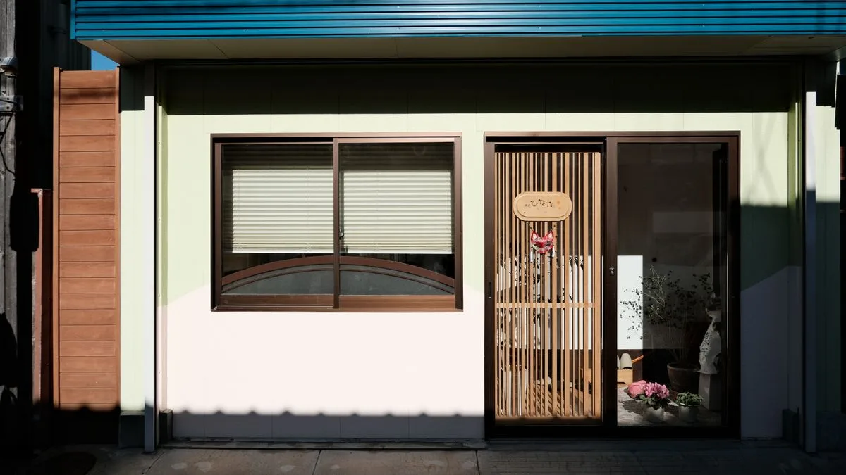 日本の住宅の玄関まわり。格子戸と窓が道路に面していて、足元にコンクリートの土間が続いている