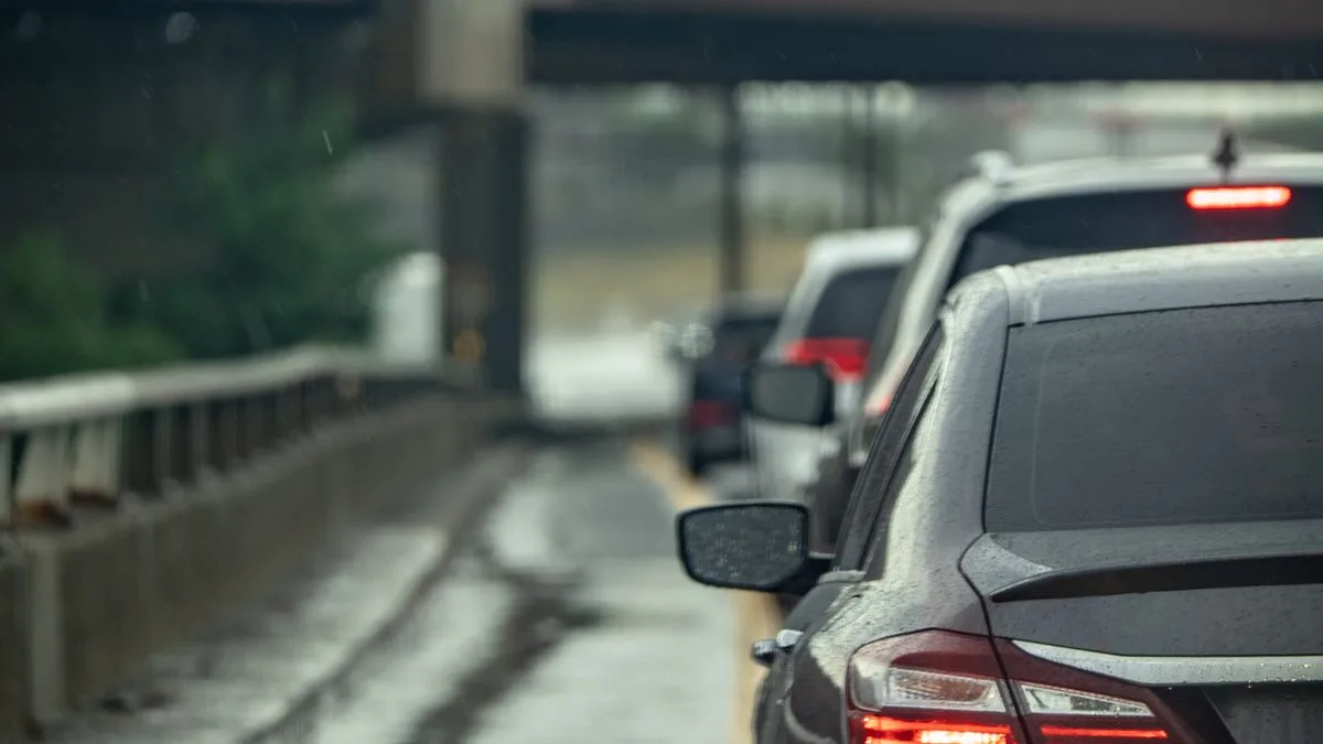 雨の中、高架下で数珠つなぎに止まっている車の列