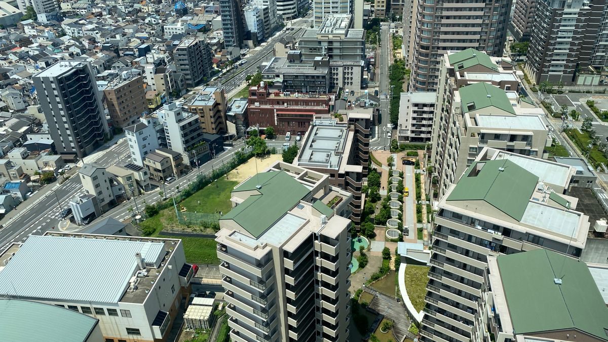 高層のタワーマンションと中層マンションが並ぶ都心の住宅街を上から見た写真
