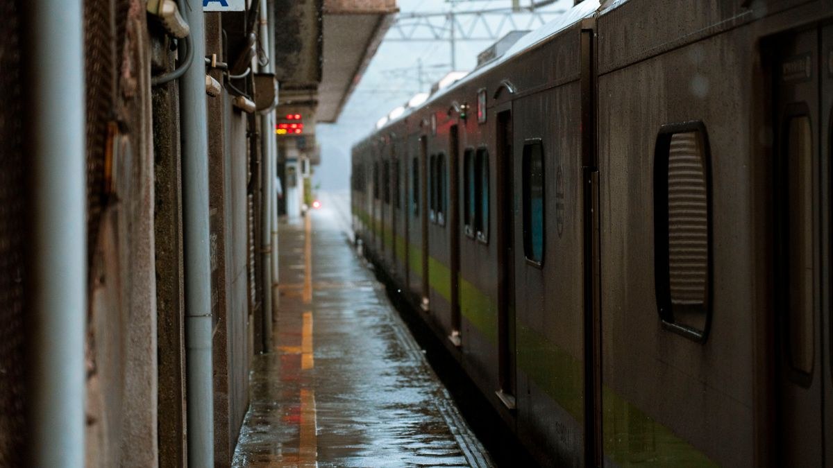 雨に濡れた駅のホームに停車している列車