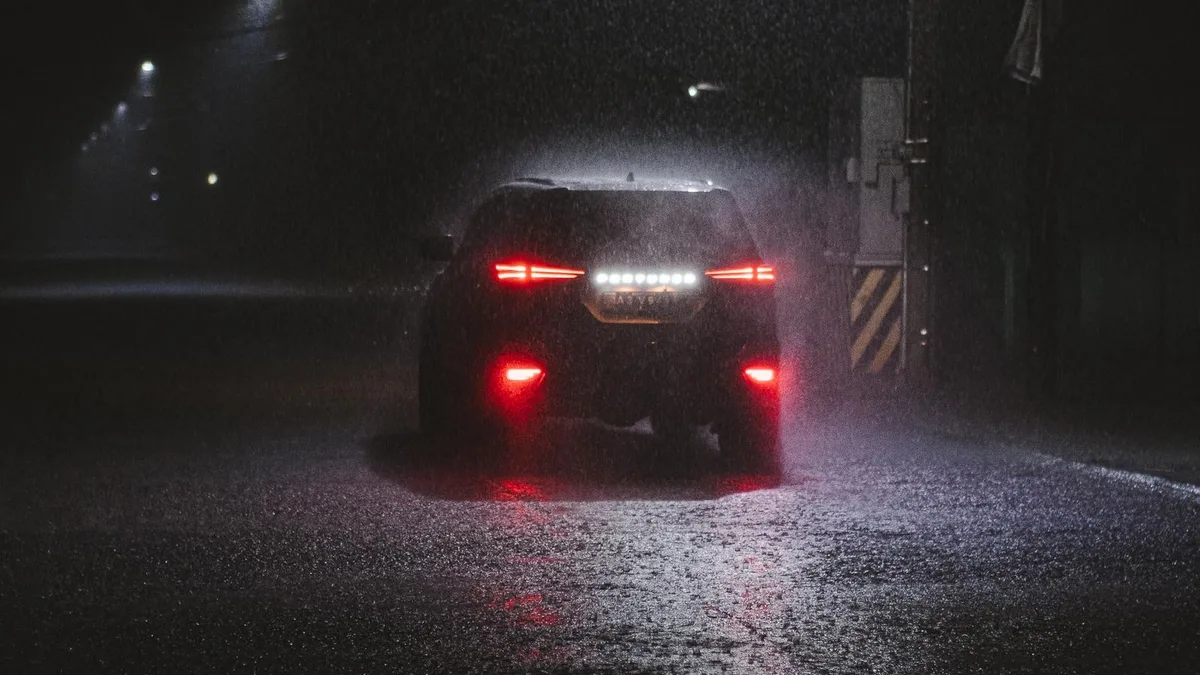 夜の大雨のなか、水しぶきを上げて走る車の後ろ姿