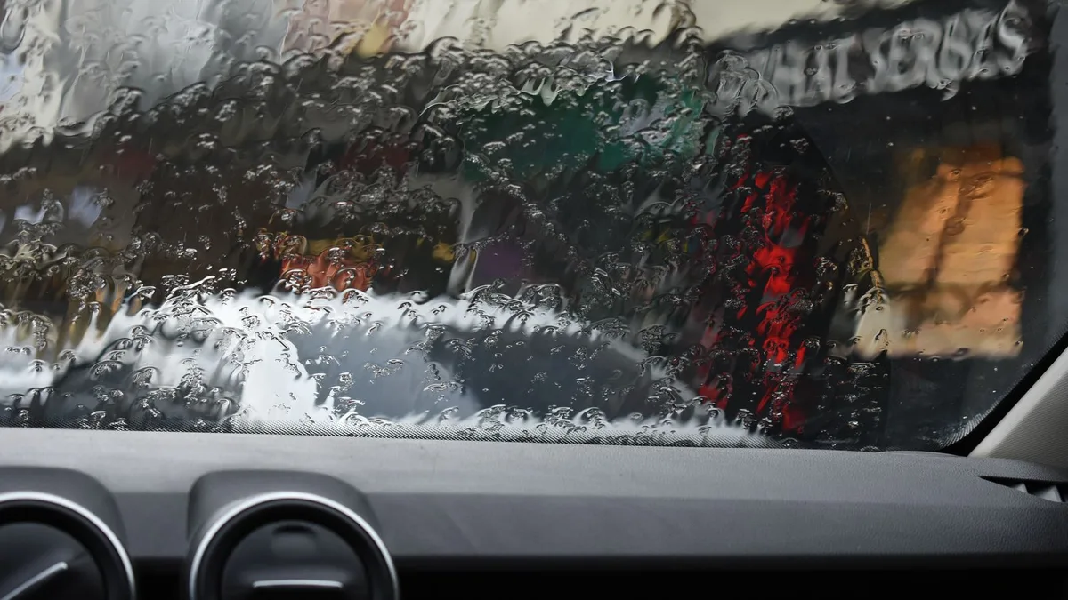 雨の日にワイパーが動くフロントガラス越しの街