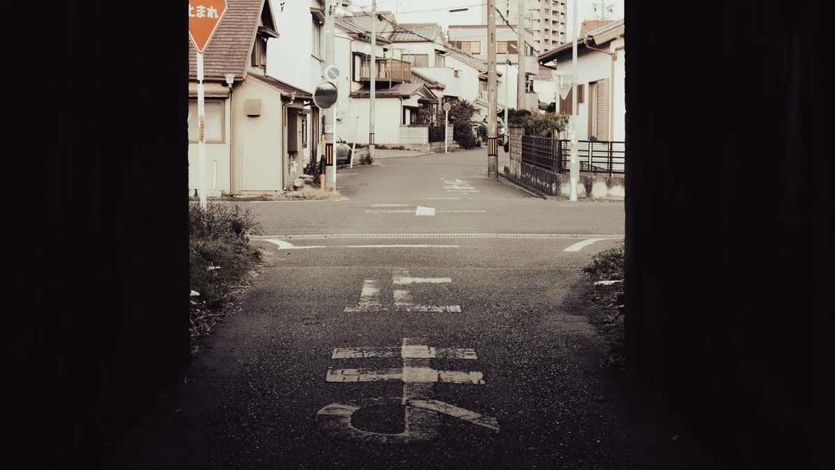 高架の下をくぐる暗い箱の向こうに、住宅街の道路と「止まれ」の標識が見えている