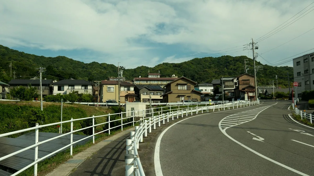 山を背にした住宅街と、そのあいだを抜けていく道路