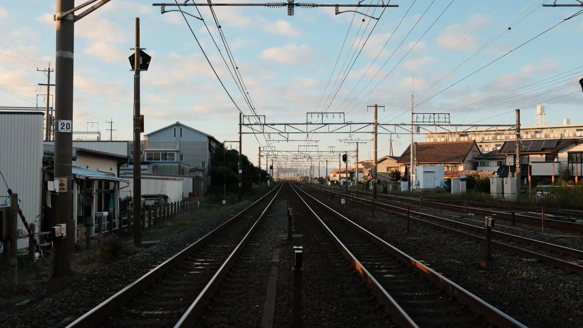 住宅街のあいだをまっすぐ抜けていく線路と、夕方の空