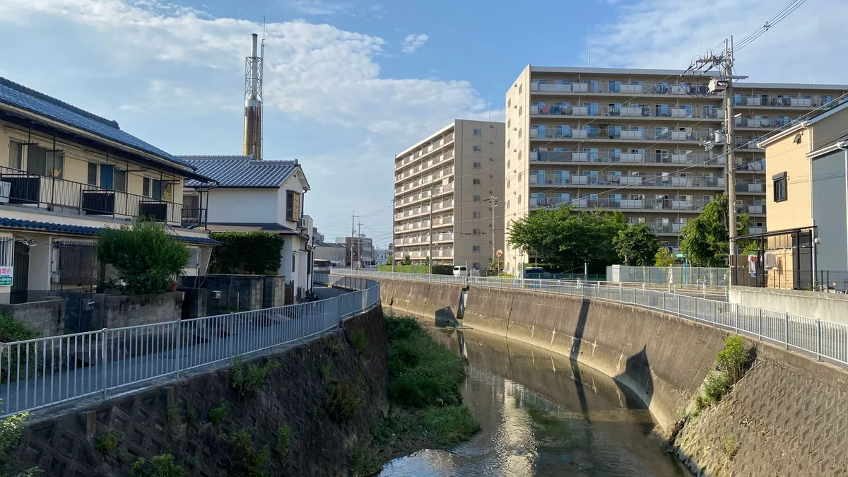 川沿いに建つ集合住宅と、その足元を流れる川