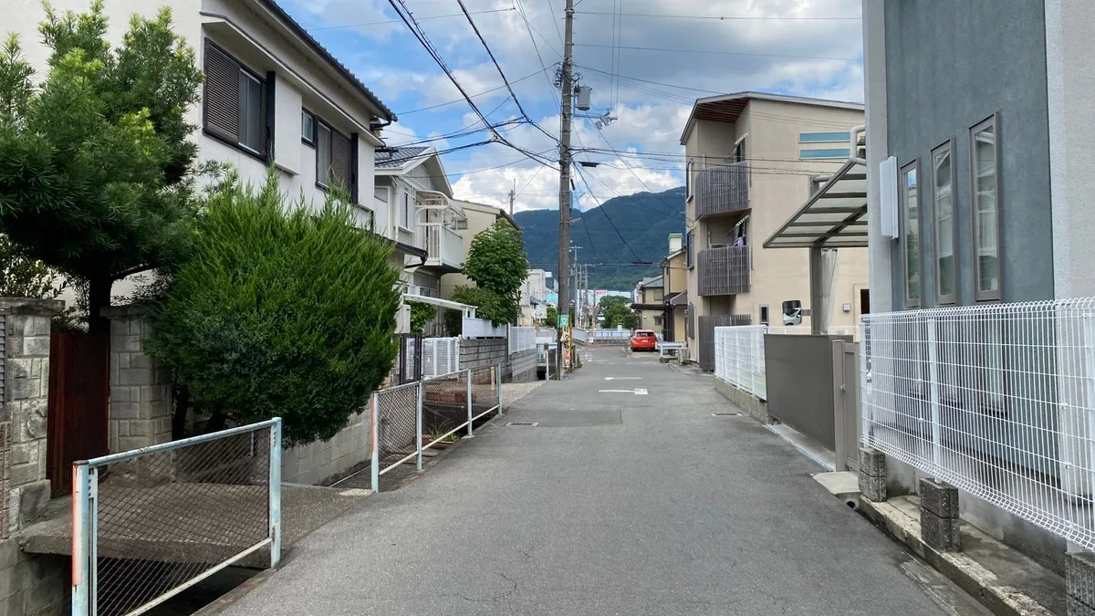 山を背にした住宅街の坂道。手前に側溝がある