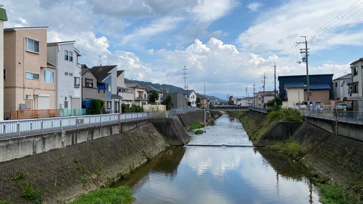 住宅のあいだを流れる水路と、雲の映り込んだ水面
