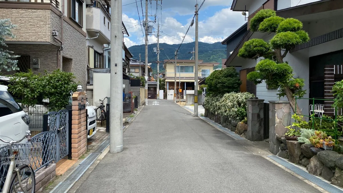 山を背にした住宅街の道と、生け垣のある家並み