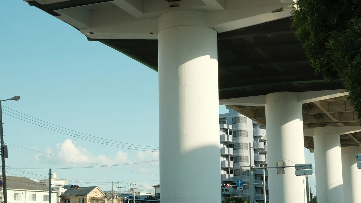 高いところを通る道路の下をくぐる、細い道