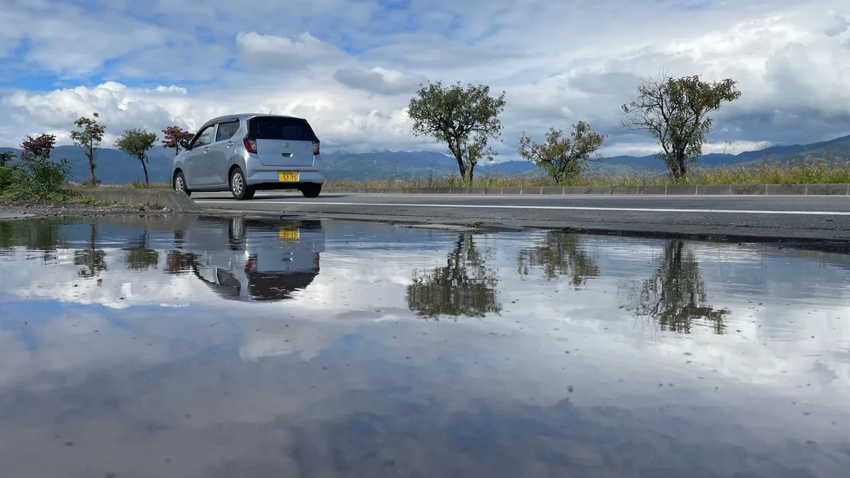 雨で濡れた道路に映り込む車