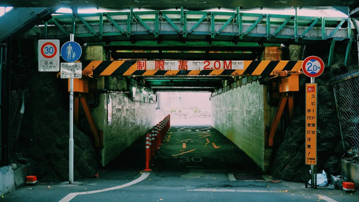制限高の標識が掛かった、線路の下へ下っていく日本の道路