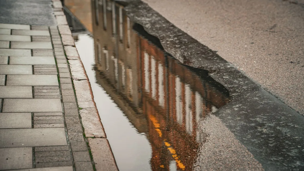 雨あがりの歩道にできた水たまりに、向かいの建物が逆さまに映っている