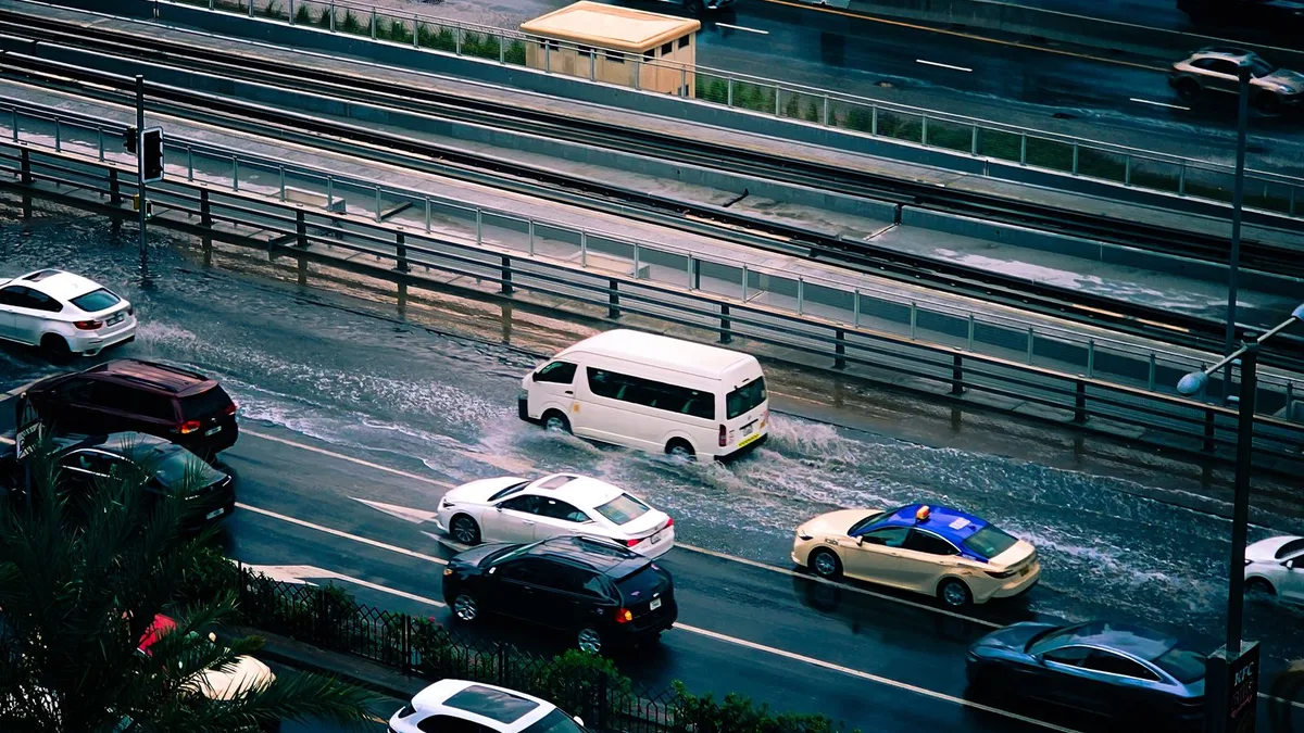 広い道路にたまった水の中を、何台もの車が進んでいる