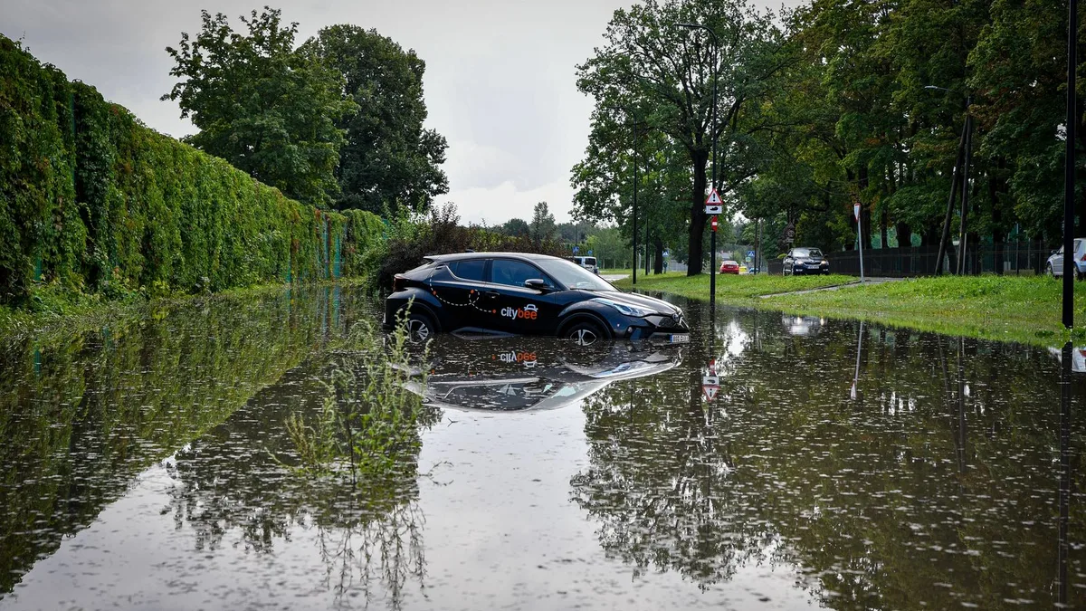 冠水した道に、屋根の近くまで水に浸かった車が取り残されている