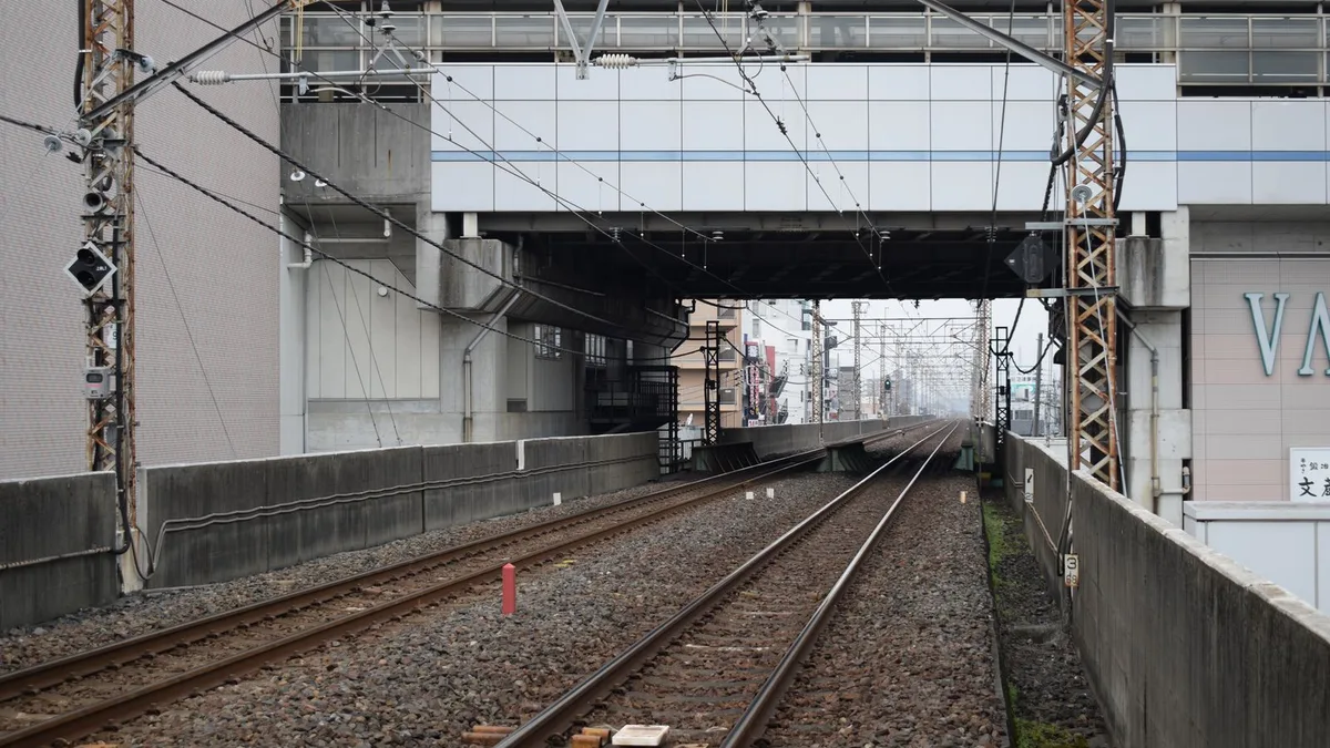 高架の下をくぐる鉄道の線路と、その先に続く街並み