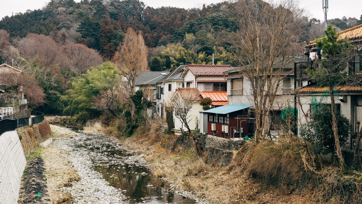 斜面のすぐ下を流れる川と、川べりに並ぶ住宅