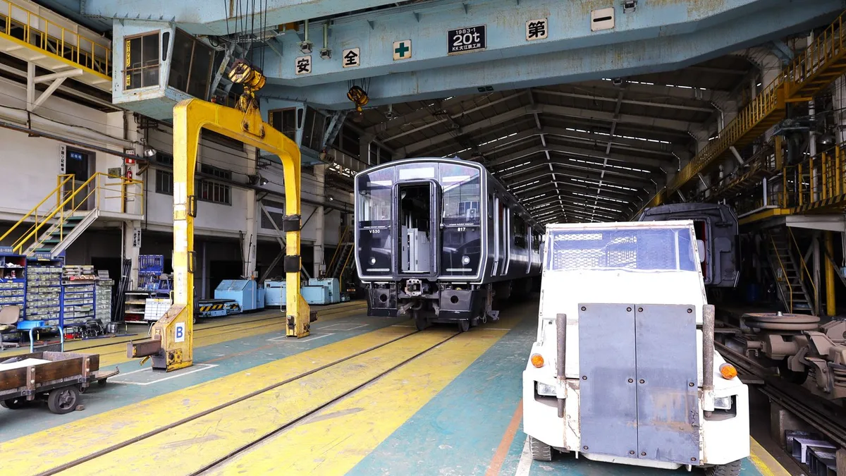 屋根のある車両基地に、電車と作業用の車両が並んでいる