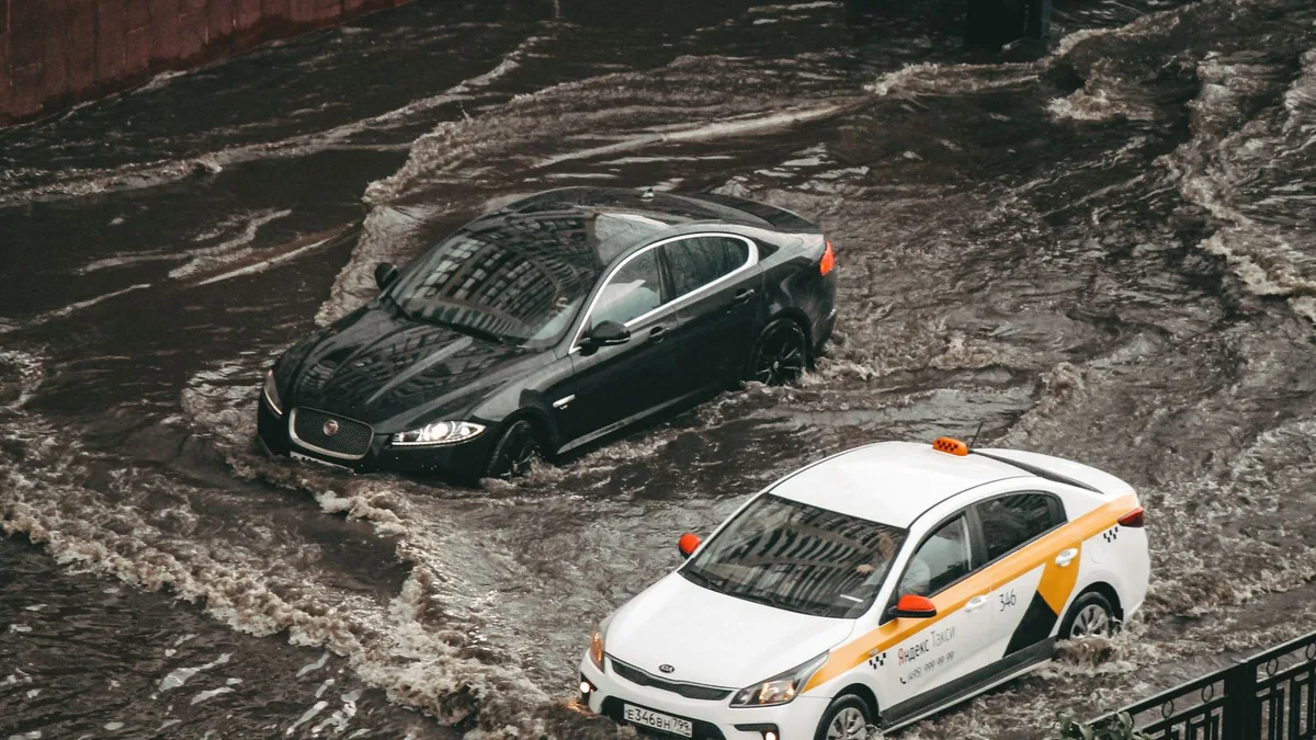 冠水した道の真ん中で、水に浸かって動けなくなった車が2台止まっている