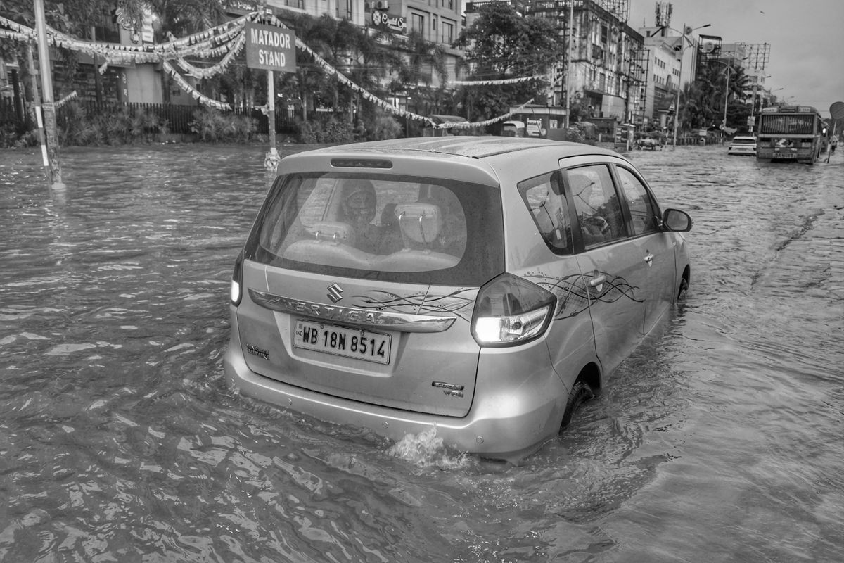 冠水した道路を走行する乗用車。タイヤの半分ほどまで水に浸かっている