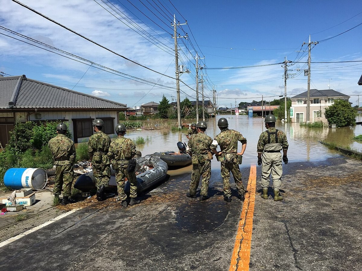 浸水した住宅地の縁に立つ陸上自衛隊員とボート（茨城県常総市、2015年9月11日）
